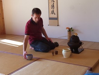 The host has prepared a bowl of tea that he places on the outside of his tatami.
